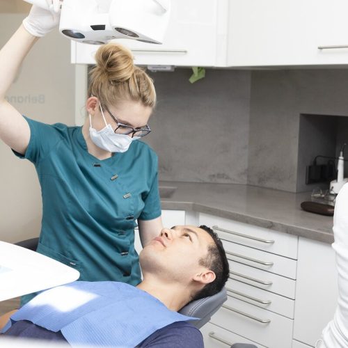 Die Ärztin schaut den Patienen an, der auf dem Behandlungsstuhl sitzt. An der Seite ist eine zahnarzthelferin zu sehen, die in der Zahnarztpraxis Dr. Franziska Höhne in Leipzig-Connewitz alles für die Untersuchung vorbereitet.